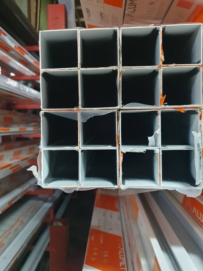 ปลายเส้นอลูมิเนียมกล่อง 1.6 × 1.6 นิ้ว มัดรวมกันบนชั้นในร้าน เห็นหน้าตัดสี่เหลี่ยมจัตุรัส